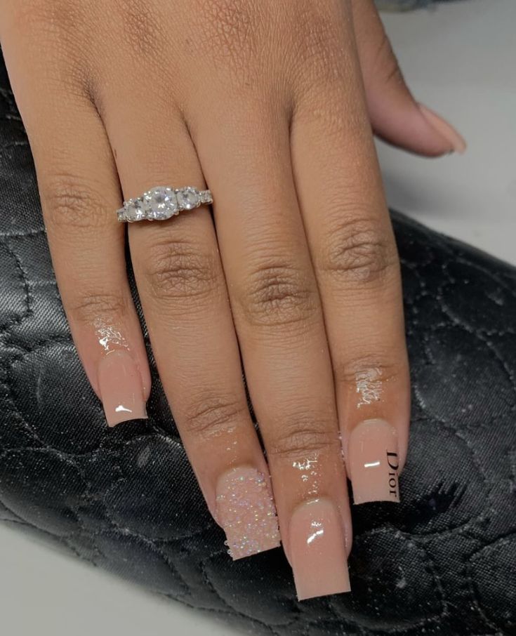 Elegant Nude Nail Design with Sparkling Accents and Complementary Ring.