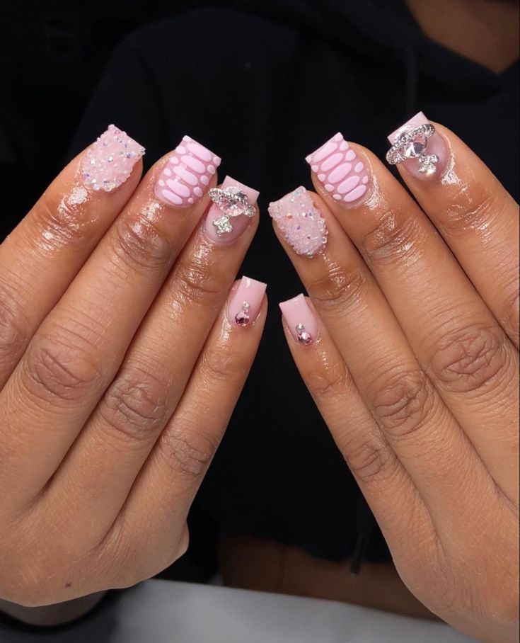 Elegant Soft Pink Nail Design with Creative Embellishments and Unique Textures.