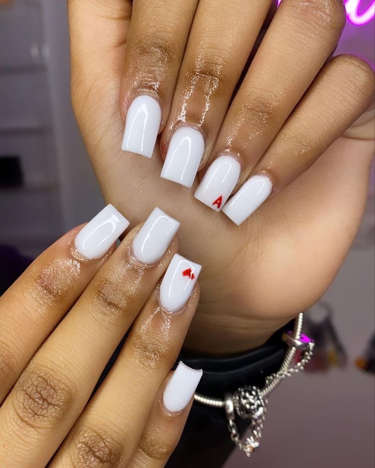 Elegant Glossy White Manicure with Playful Red Heart Accents