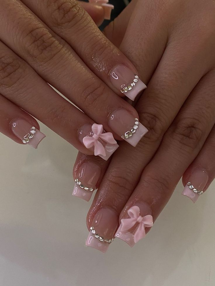 Charming Soft Pink Nail Design with Glossy Finish, Delicate Bows, and Sparkling Rhinestones.