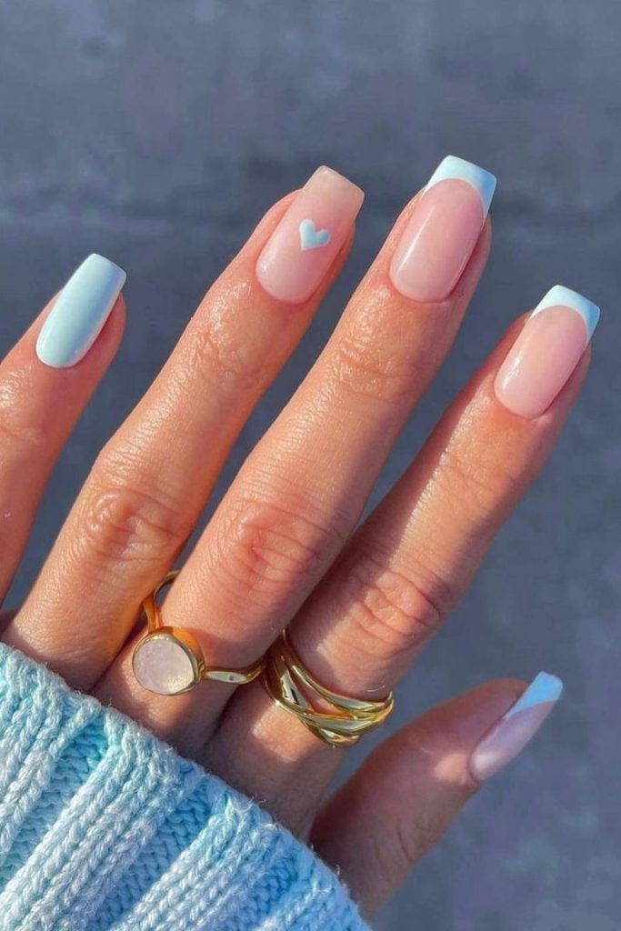 Charming Pastel Nail Design with Light Blue Tips and Playful Heart Accent.