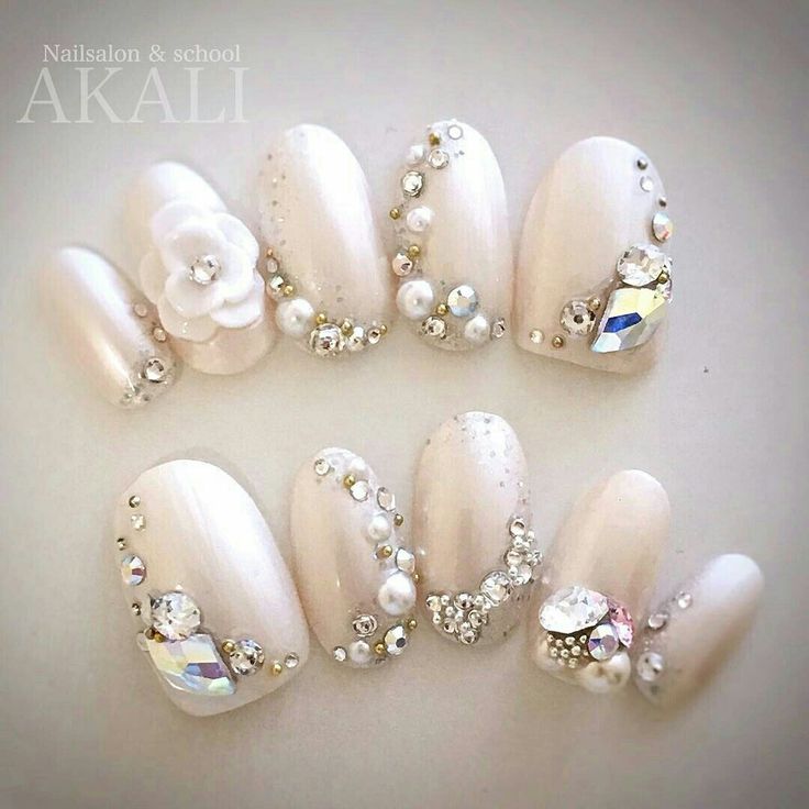 Sophisticated Nail Design: Cream Base with Intricate Rhinestone, Pearl Accents, and Elegant Floral Embellishment.