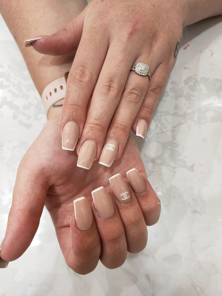 Sophisticated Nail Design: Glossy Nude Base with White French Tips and Iconic Logo Accents.