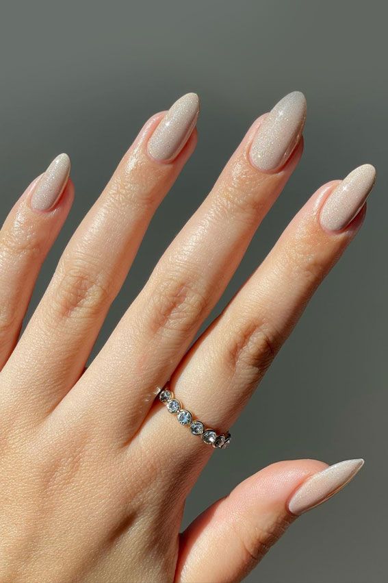 Sophisticated Almond-Shaped Nails with Subtle Shimmer and Elegant Ring Accents