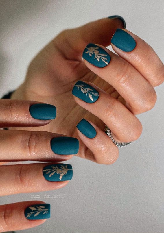 Elegant Matte Teal Nails with Intricate Gold Leaf Designs for Chic Sophistication.