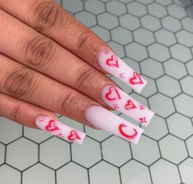 Whimsical Elongated Square Nails: Soft Matte White with Playful Red Hearts and Crescents for a Romantic Modern Look.