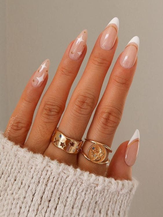 Chic Nail Design: Soft Neutrals with Classic White Tips and Abstract Patterns, Accentuated by Gold Rings.