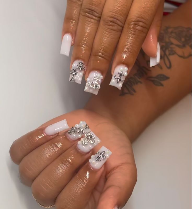 Sophisticated Soft White Nail Design with Floral Embellishments and Rhinestones.