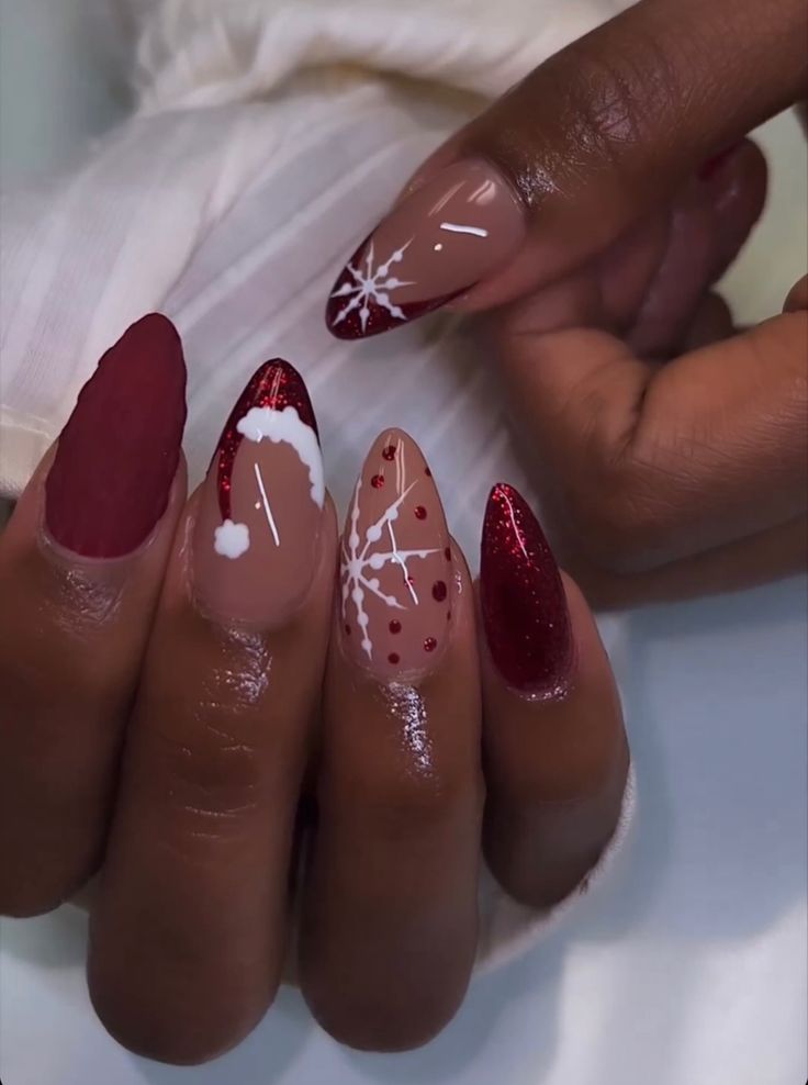 Festive Winter Nail Design: Deep Red, Nude Shades, and Sparkling Glitter with Snowflake Accents.