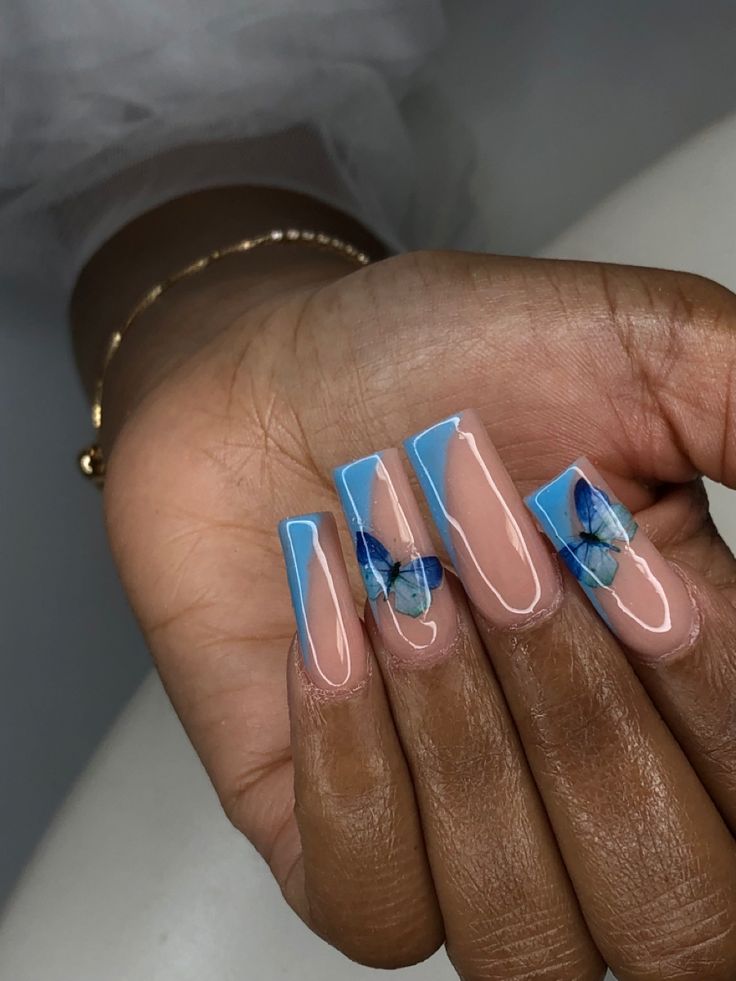 Whimsical Nail Design: Soft Blue and Nude with Butterfly Graphics and Geometric Shapes.