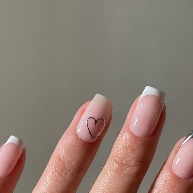 Chic Minimalist Nail Design: Nude Base with French Tips and Playful Heart Accent.