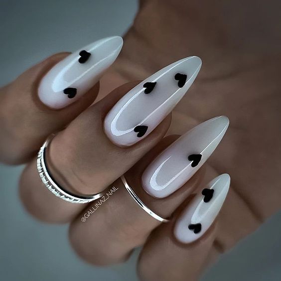 Chic Almond-Shaped Nails with Glossy White Base and Playful Black Heart Accents