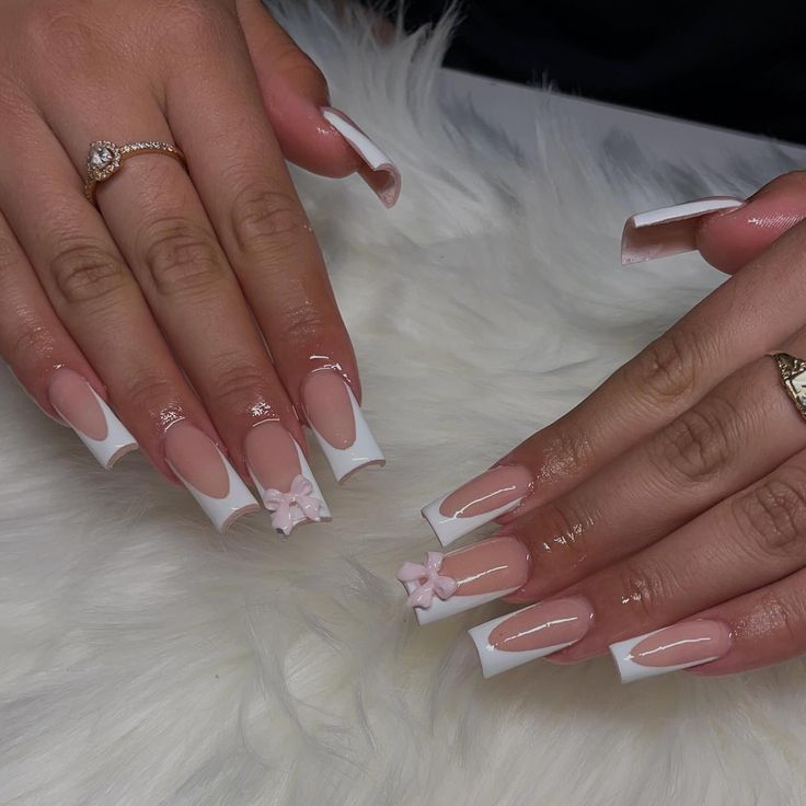 Chic Nude and White Nail Design with Delicate Pink Floral Embellishments.