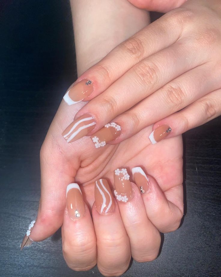 Chic and Playful Elegant Nail Design with Neutral Base, White French Tips, Floral Patterns, and Sparkling Accents.