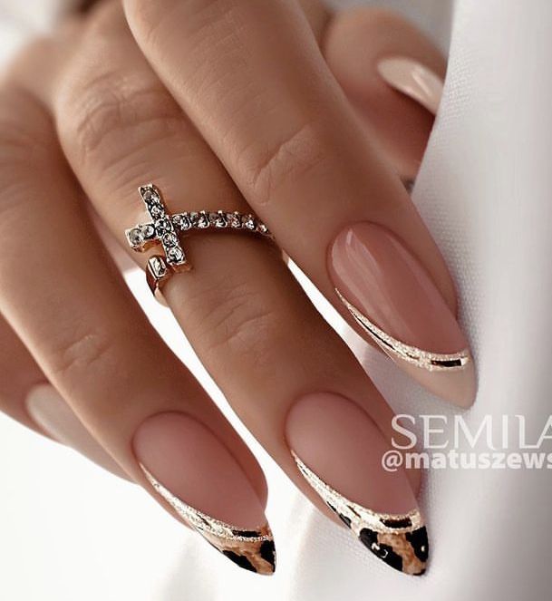 Chic Almond-Shaped Nude Nails with Glamorous Gold Tips and Rhinestone Accent Ring.