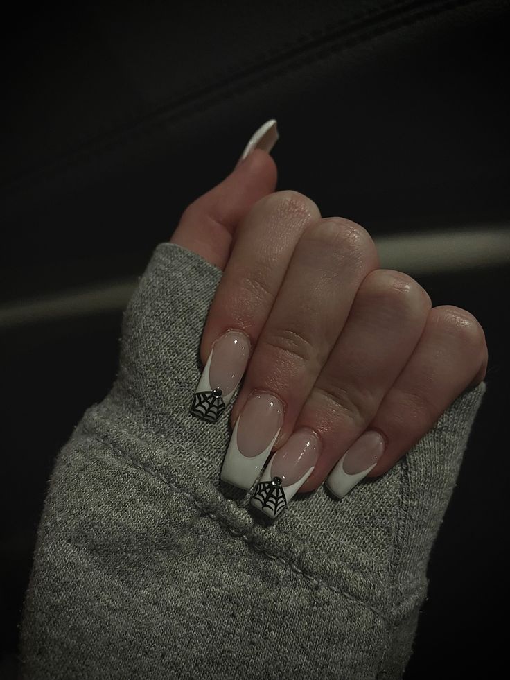 Sophisticated French Manicure with Playful Spider Web Accents for a Stylish Seasonal Look.