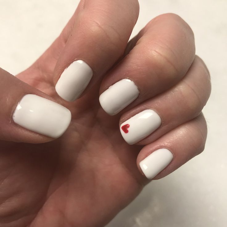 Elegant White Nail Design with Subtle Red Heart Accent for a Minimalist Romantic Look.