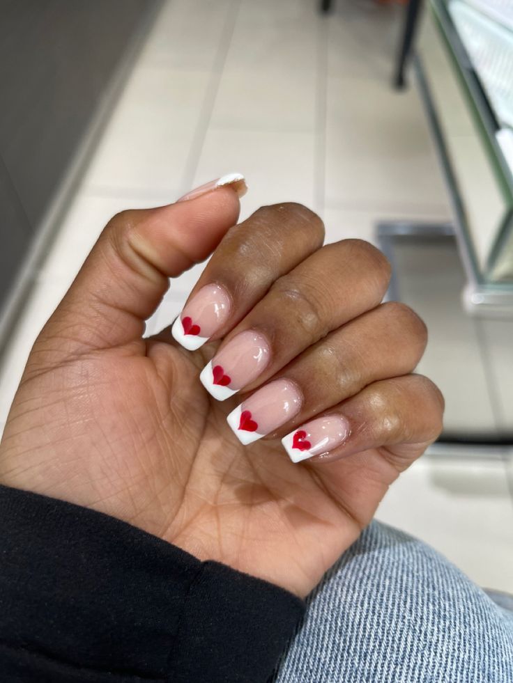 Flirty Nail Design with Natural Base, Classic White Tips, and Playful Red Heart Accents.