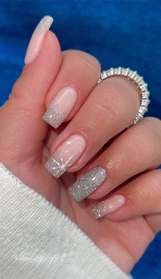 Elegant winter nail design with soft pink to shimmering silver gradient and delicate snowflake accents.