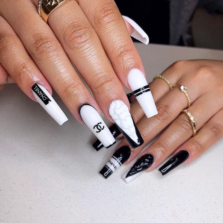 Sophisticated Monochrome Nail Design: Glossy Black and White with Bold Patterns and Embossed Details.