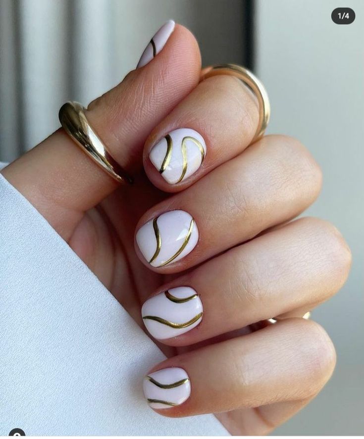 Chic Light Pink Nail Design with Flowing Gold Accents for Sophisticated Elegance.