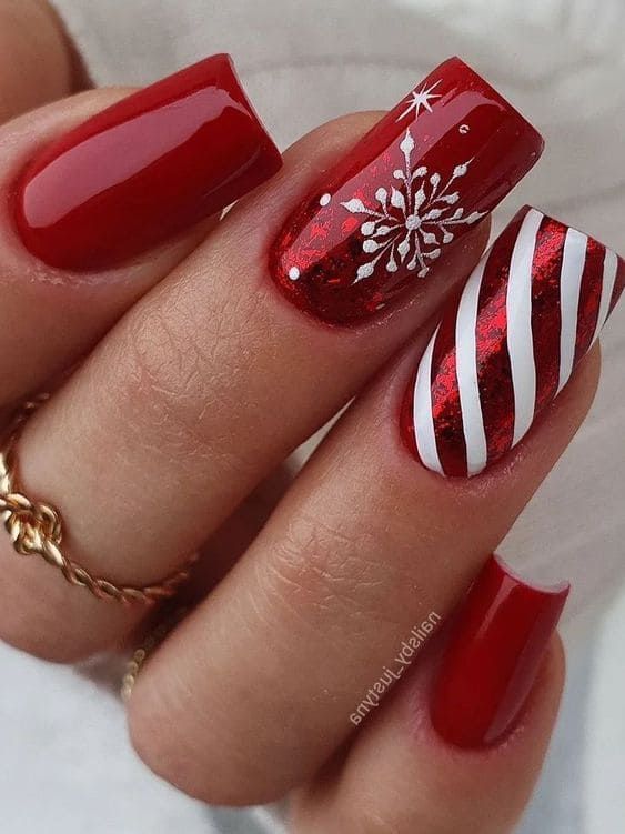 Holiday Nail Art: Glossy Red Base with Glittery Snowflakes and Candy Cane Stripes.