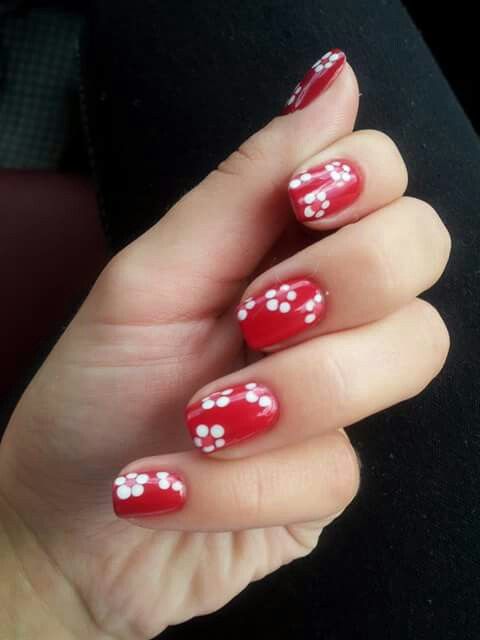 Charming Red Nails Embellished with Whimsical White Floral Accents.