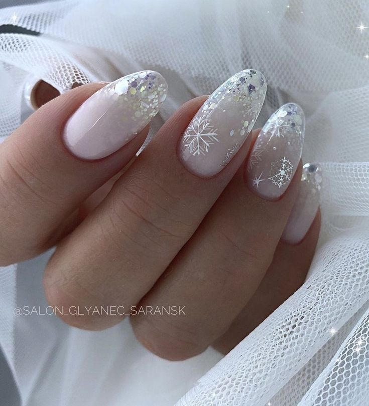 Chic Winter-Inspired Nail Design: Soft Nude Gradient with Glitter and Snowflake Accents.