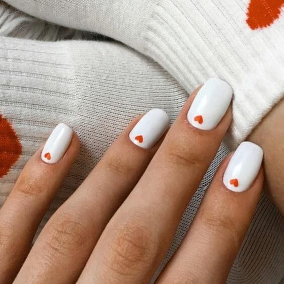 Charming White Nail Design with Delicate Orange Heart Accents for a Cozy Aesthetic.