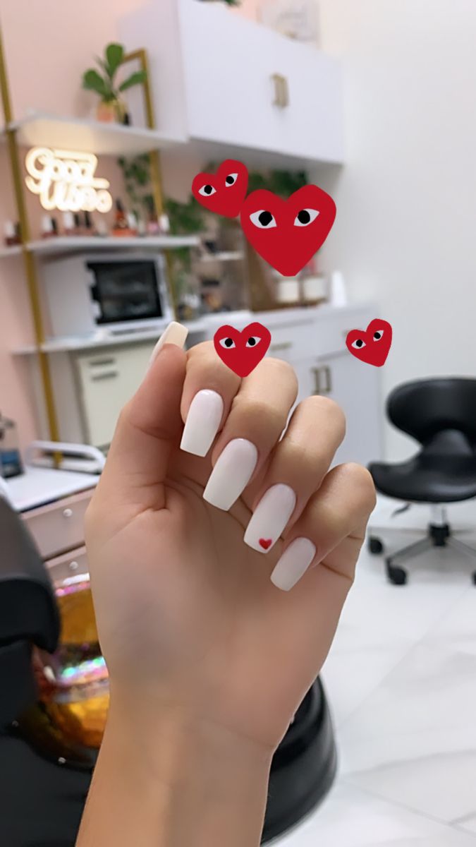 Chic White Square Nails with Whimsical Red Heart Accent in a Modern Nail Salon Setting.