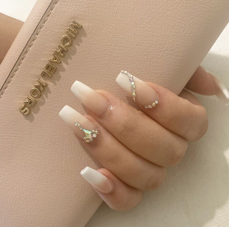 Sophisticated Nail Design: Nude Base with French Tips and Rhinestone Accents.