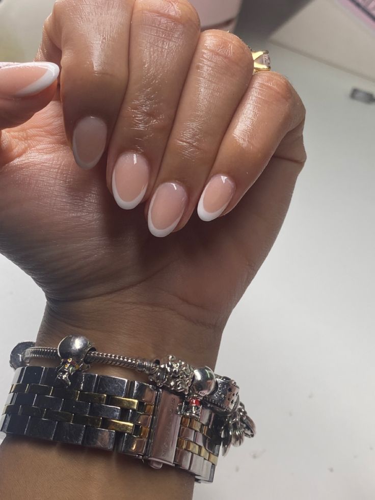 Timeless French Manicure: Elegant Nude Nails with Classic White Tips and Chic Bracelet Accents.