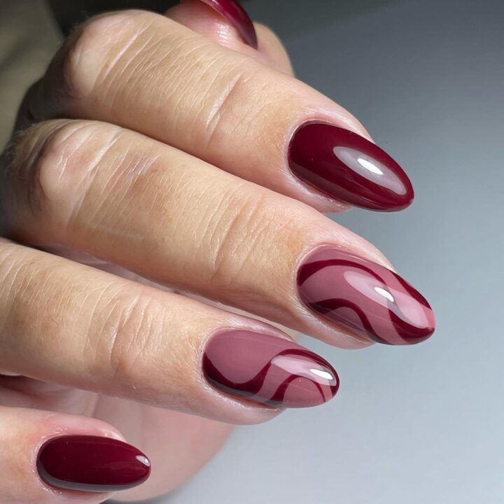 Dynamic Burgundy Nail Design with Glossy Finish and Artistic Patterns.