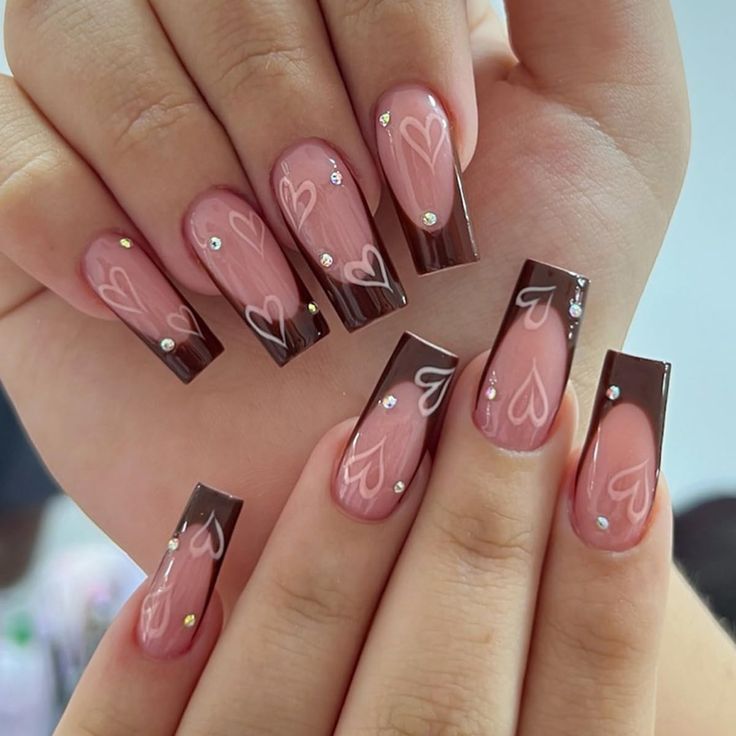 Chic Romantic Manicure: Soft Pink and Rich Brown Nails Embellished with Heart Patterns and Gemstones.