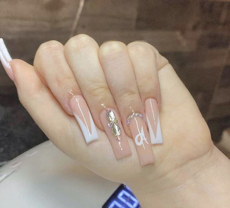 Sophisticated Nude and White Nail Design with Glamorous Embellishments.