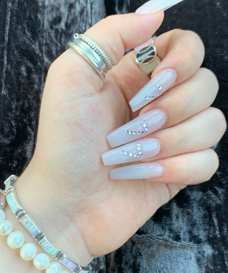 Chic Long-Shaped Milky White Nails Enhanced with Rhinestones for a Sophisticated Look.