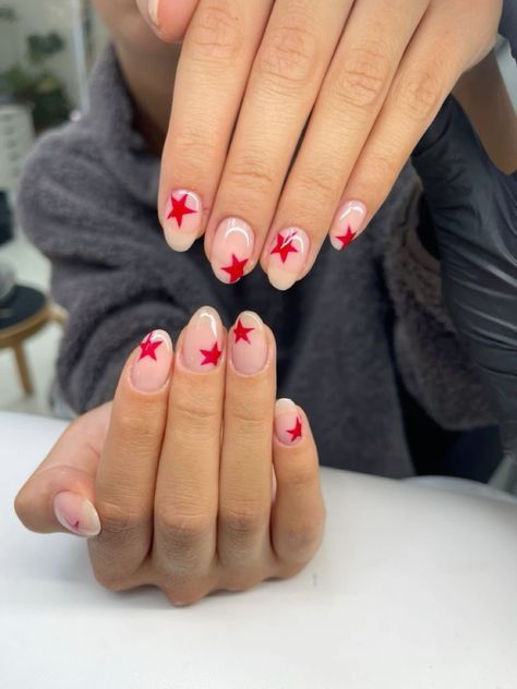 Striking Star-Themed Nail Design: Bold Red Stars on Elegant Nude Base.