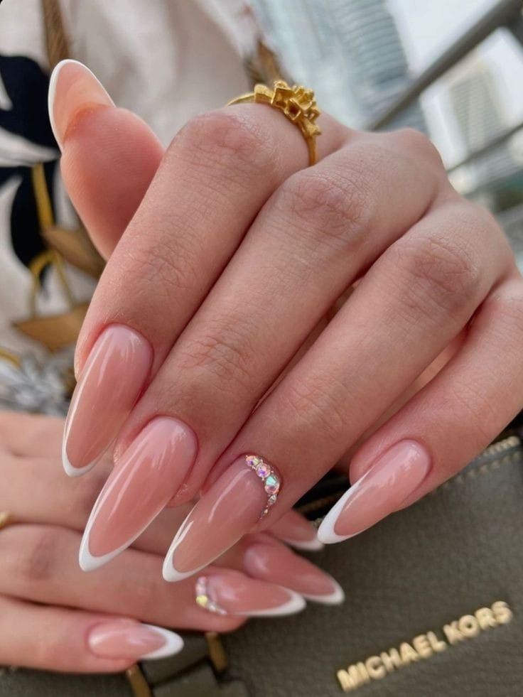 Chic French Manicure: Elegant Almond Nails with Soft Nude Base and Sparkling Gemstone Accent.