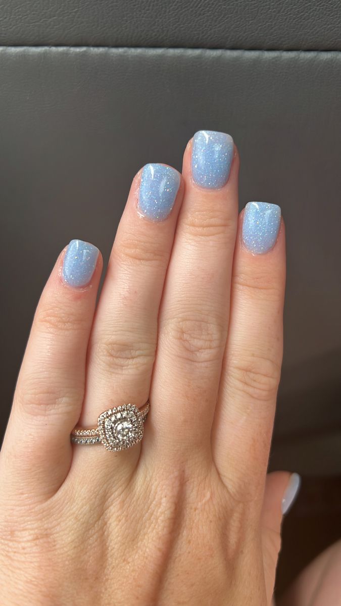 Elegant Soft Blue Glitter Nails with Gradient Effect and Sparkling Ring.