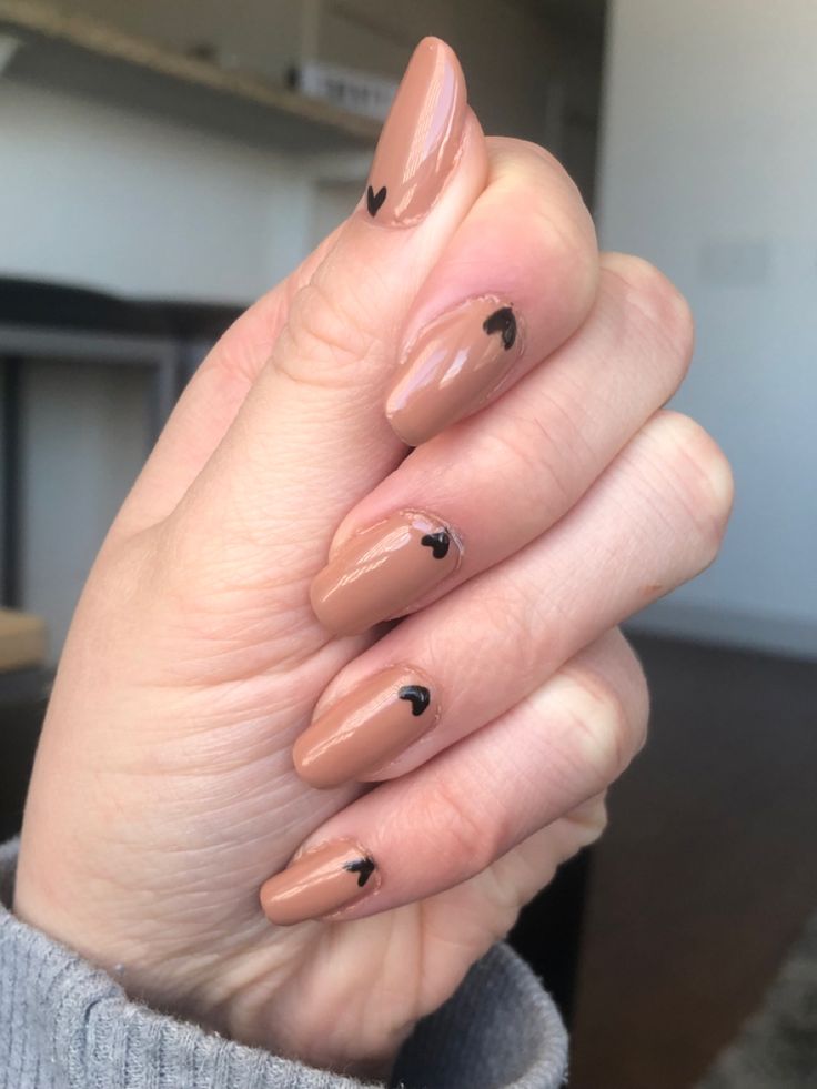 Elegant Nude Nail Design with Black Heart Accents: A Chic Minimalist Style for Any Occasion.