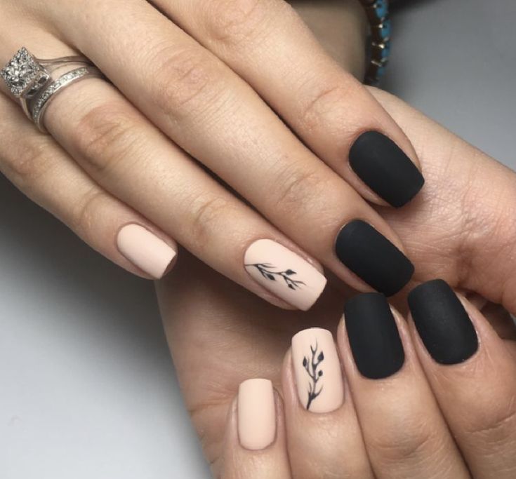 Sophisticated Matte Black and Soft Nude Nail Design with Elegant Botanical Motifs.