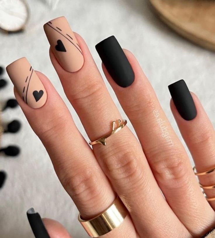 Chic Matte Black and Nude Nail Design with Heart Accents and Line Art.