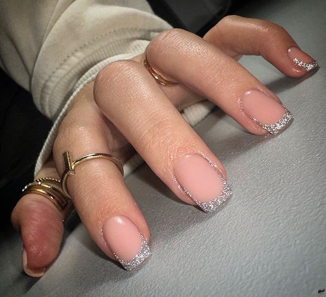 Chic French-Inspired Nail Design with Nude Base and Sparkling Silver Tips.