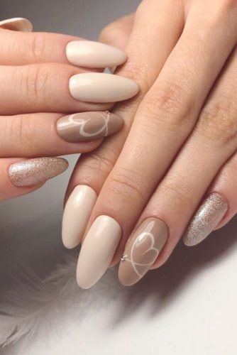 Chic Nude and Beige Nail Design with Romantic Heart Accents and Glamorous Gold Highlights.