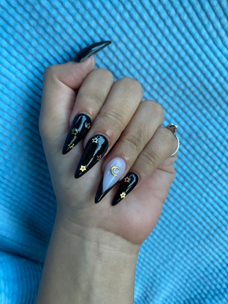 Celestial-Inspired Stiletto Nails: Bold Black Base with Gold Accents and Gradient Effect for Nighttime Elegance.