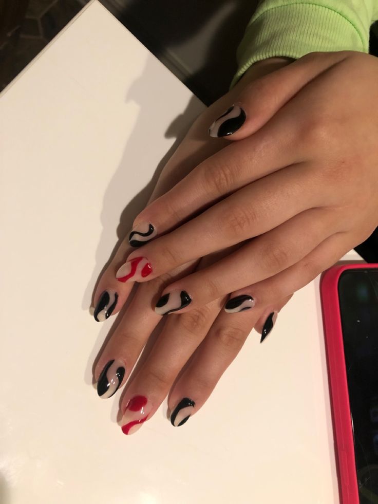 Modern Nail Art: Bold Black, Vibrant Red, and Elegant Beige Swirls.