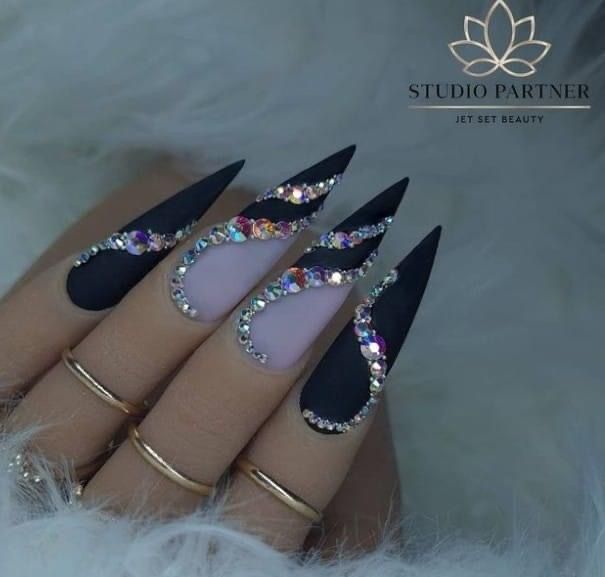 Glamorous Stiletto Nails: Matte Black and Soft Lavender with Dazzling Rhinestone Waves.