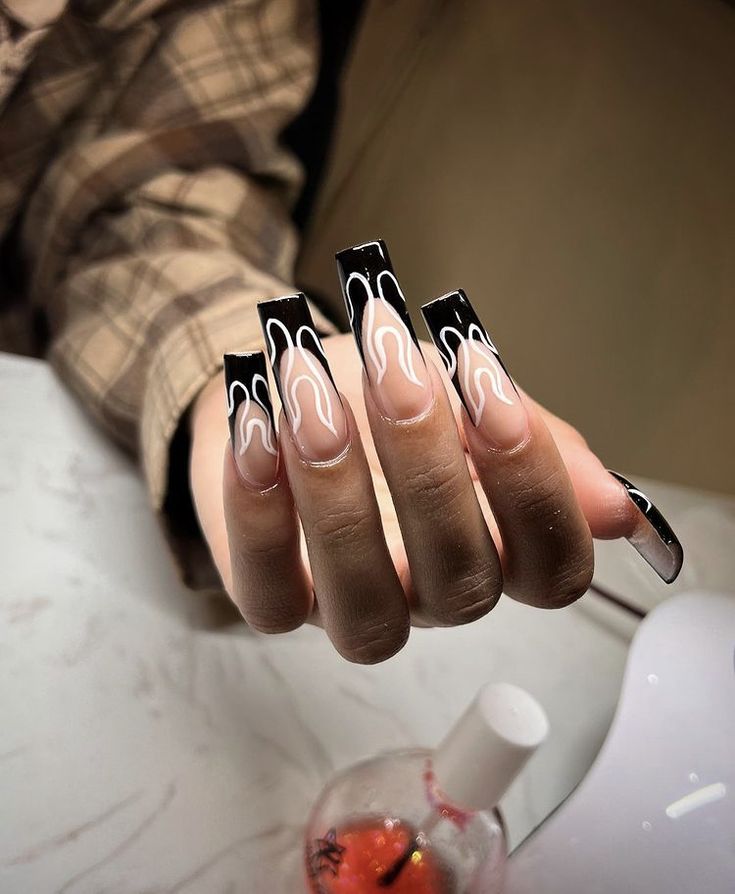 Bold Black and White Flame Nail Design with Glossy Finish on Subtle Nude Base.