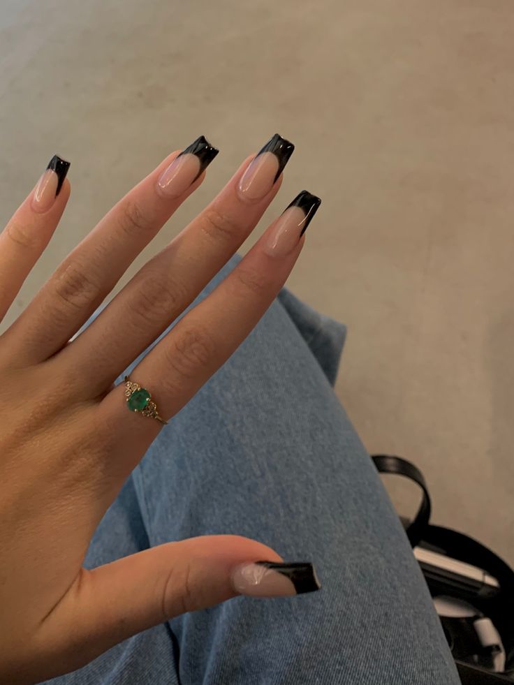 Chic French Tip Nails with Bold Black Finish and Elegant Green Gemstone Ring.