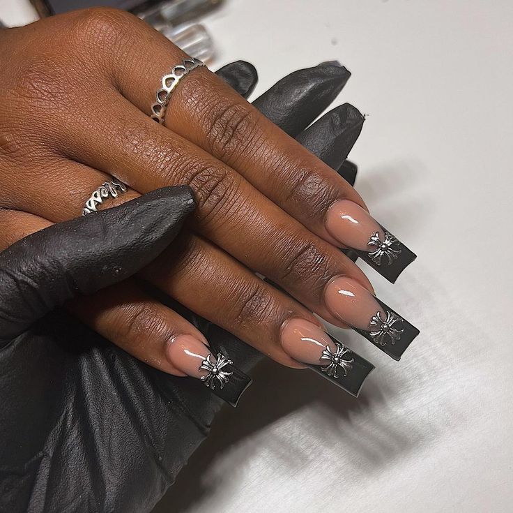 Sophisticated Square Nail Design with Nude and Black Polishes and Floral Accents.